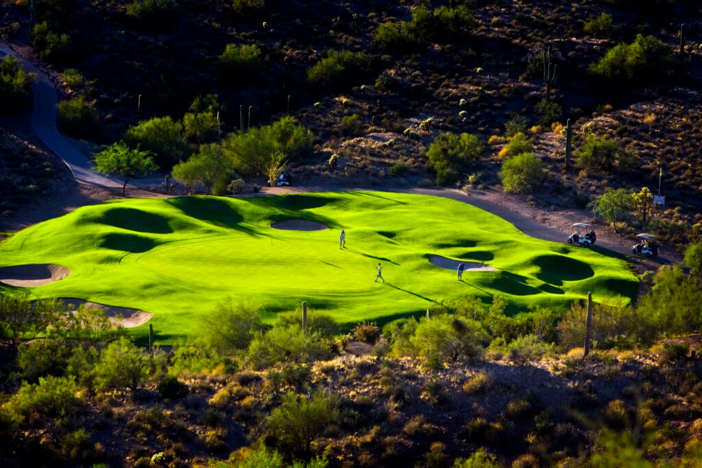 Green golf course surrounded by rocky desert terrain