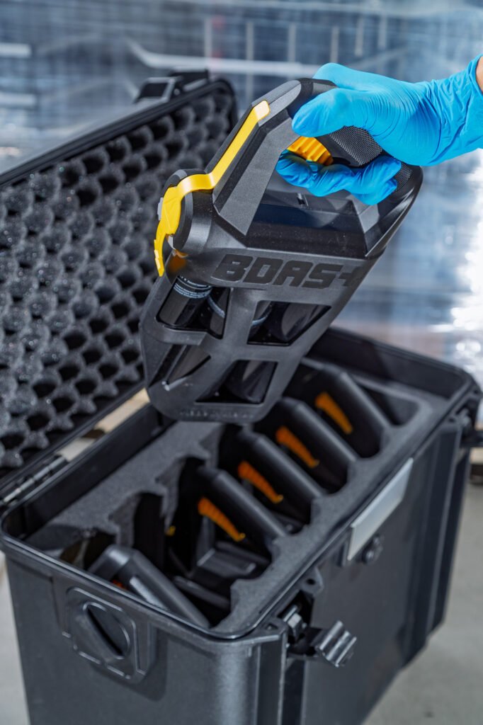Gloved hand lifting a handheld device from a fitted equipment case