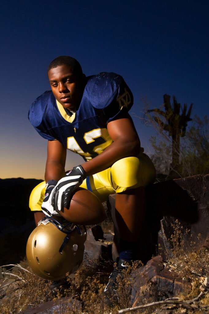 Football player seated outdoors with a gold helmet