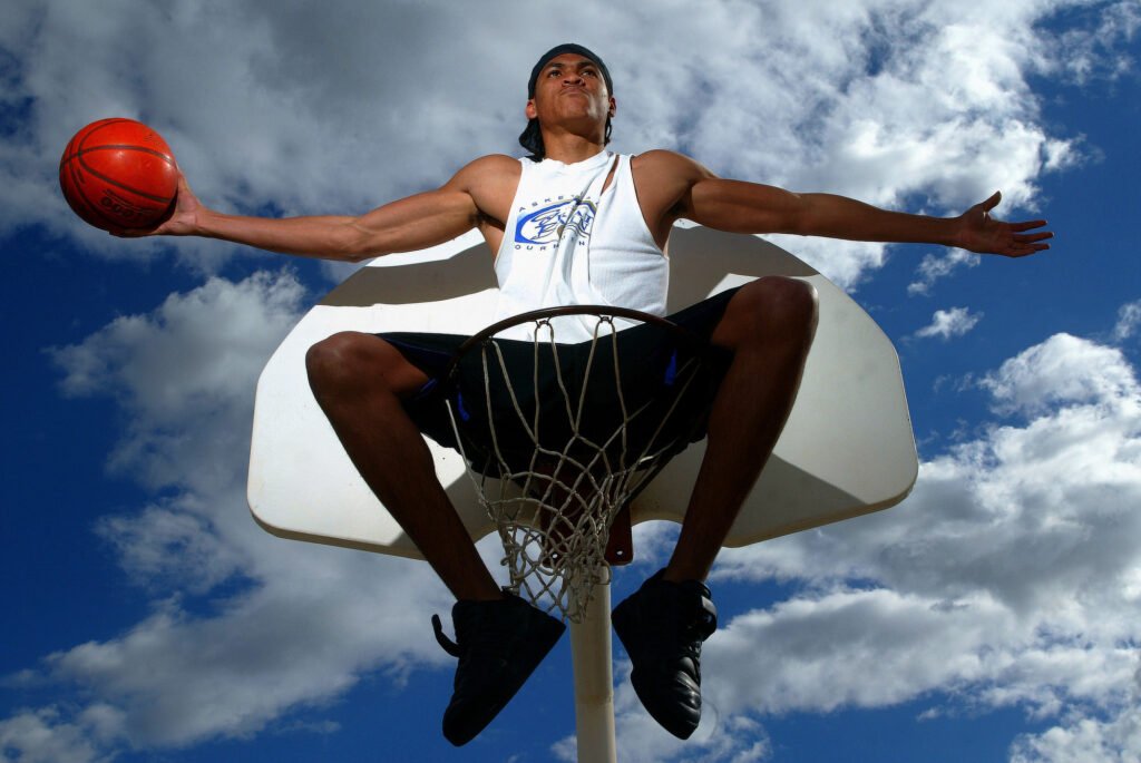 Basketball player leaping with a ball beneath a cloudy sky