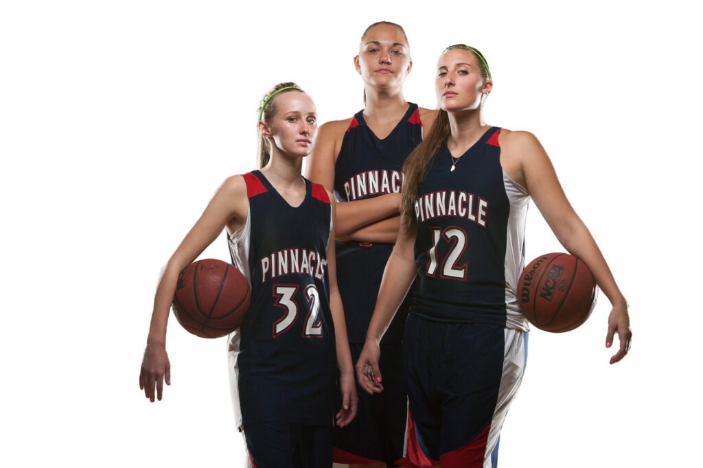 Three basketball players in dark uniforms against white