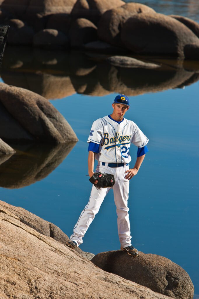 Baseball player standing on a boulder beside still water
