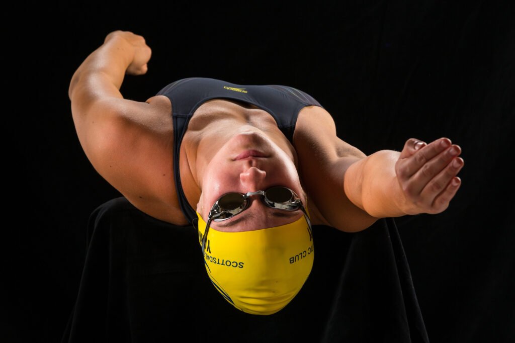Swimmer demonstrating a stroke against a black background