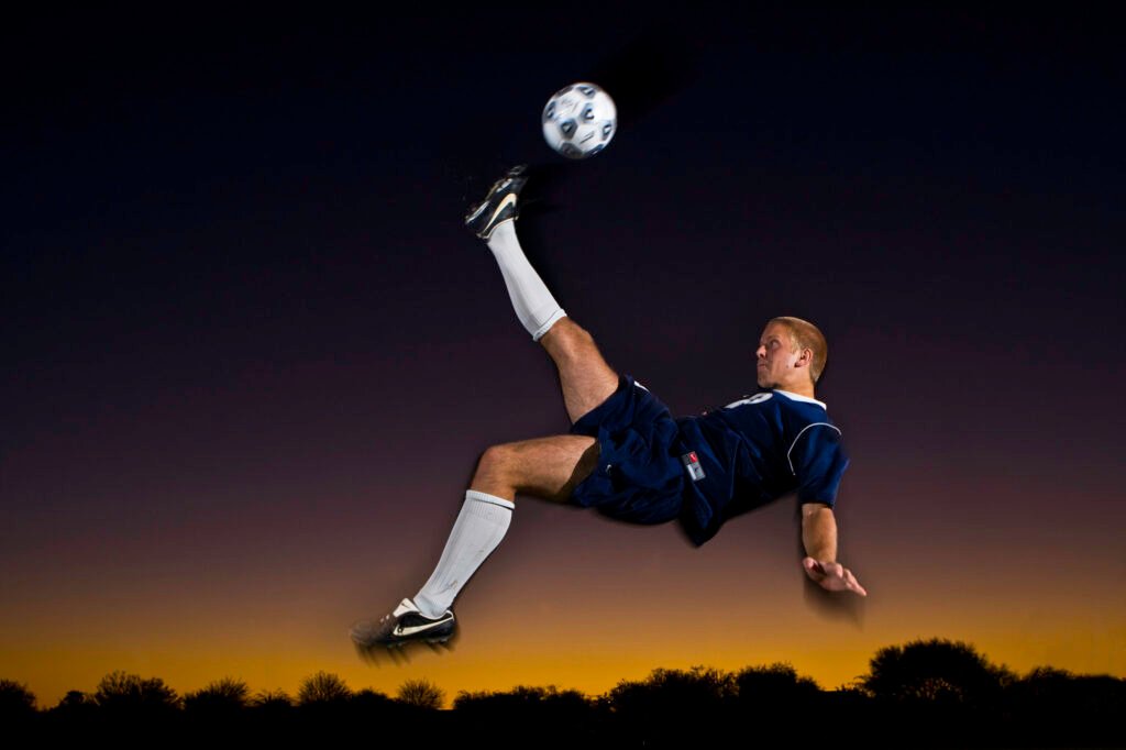 Soccer player performing an overhead kick at sunset