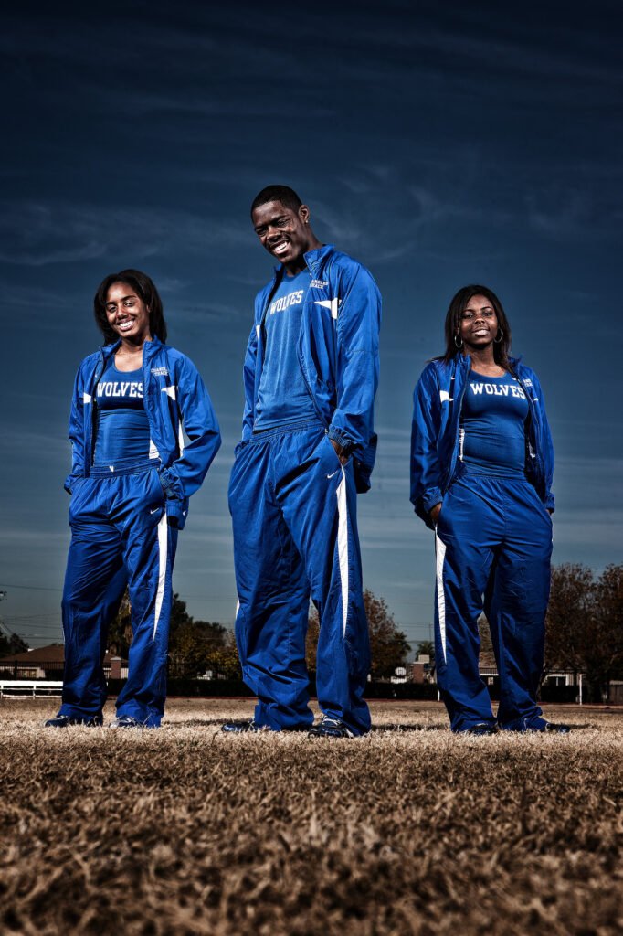 Three track athletes in blue warm-up suits outdoors